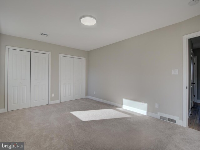 unfurnished bedroom featuring carpet and multiple closets