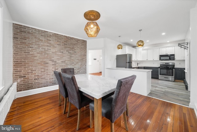 dining room featuring brick wall, sink, and light hardwood / wood-style floors