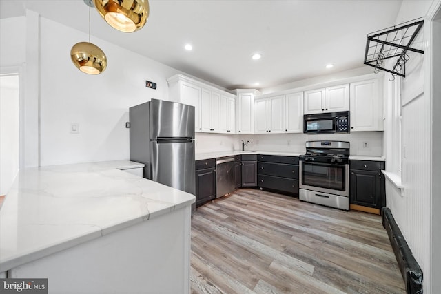 kitchen with stainless steel appliances, light stone counters, white cabinets, decorative light fixtures, and light wood-type flooring