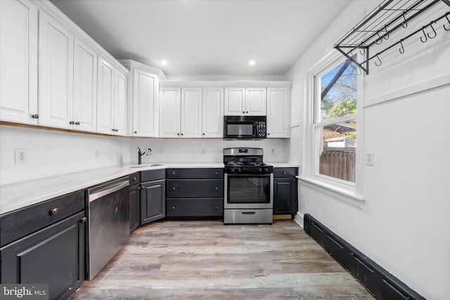 kitchen with white cabinetry, appliances with stainless steel finishes, sink, and light hardwood / wood-style flooring