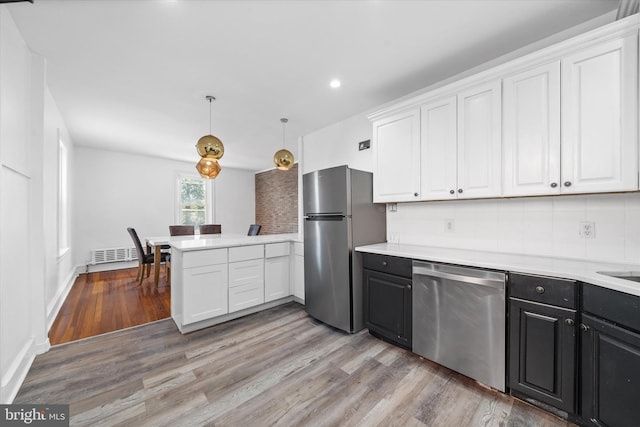 kitchen featuring tasteful backsplash, white cabinets, hanging light fixtures, light hardwood / wood-style floors, and stainless steel appliances