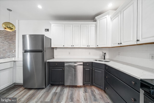 kitchen with stainless steel appliances, white cabinetry, sink, and decorative light fixtures