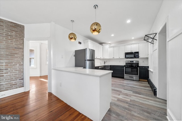 kitchen featuring appliances with stainless steel finishes, kitchen peninsula, light hardwood / wood-style flooring, and white cabinets