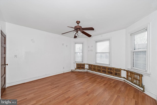 unfurnished room featuring ceiling fan, wood-type flooring, and a wealth of natural light