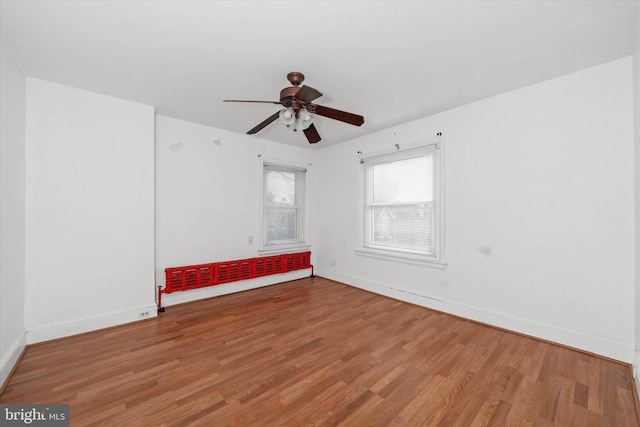 spare room with hardwood / wood-style flooring, radiator heating unit, and ceiling fan