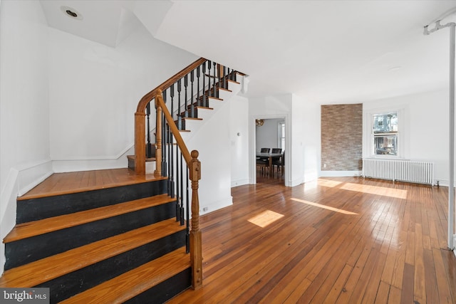 stairway featuring radiator and hardwood / wood-style floors