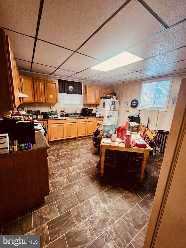 kitchen with a paneled ceiling, wooden walls, and white refrigerator