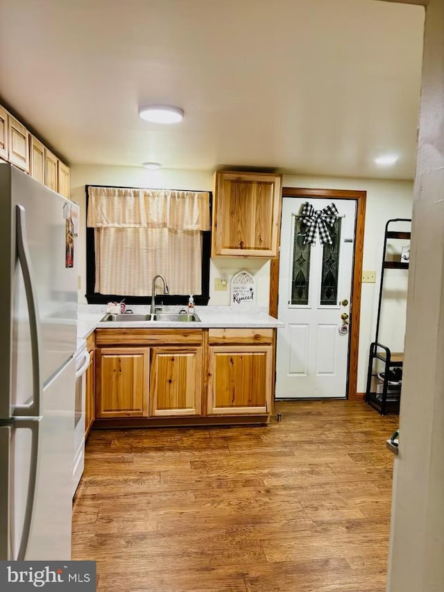 kitchen with sink, stainless steel fridge, and light wood-type flooring