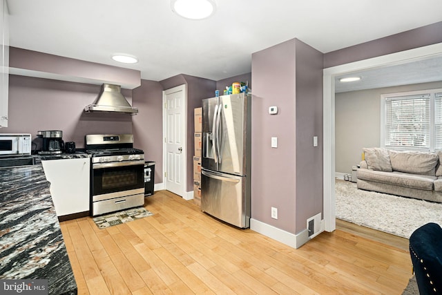 kitchen featuring light hardwood / wood-style flooring, wall chimney exhaust hood, and appliances with stainless steel finishes