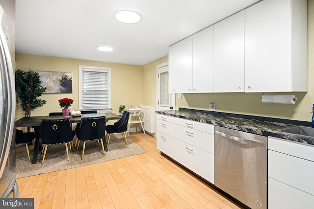 kitchen featuring a wealth of natural light, stainless steel appliances, dark stone counters, white cabinets, and light wood-type flooring