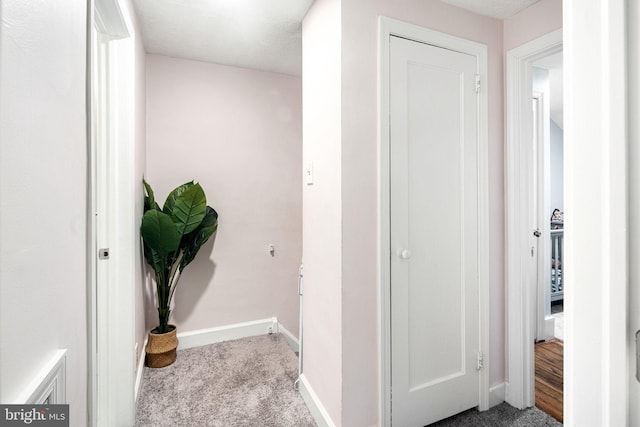 corridor with light carpet and a textured ceiling