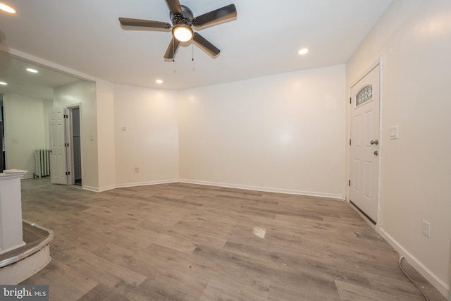 unfurnished living room featuring radiator, ceiling fan, and light hardwood / wood-style floors