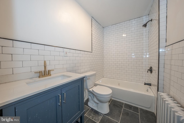 full bathroom with tile patterned floors, vanity, tiled shower / bath combo, tile walls, and radiator heating unit