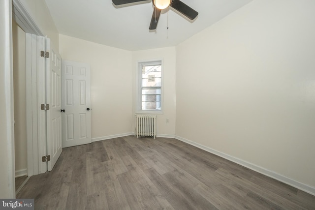 spare room with hardwood / wood-style flooring, radiator, and ceiling fan