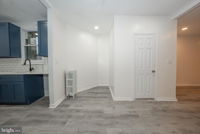 interior space featuring decorative backsplash, radiator heating unit, hardwood / wood-style floors, and sink