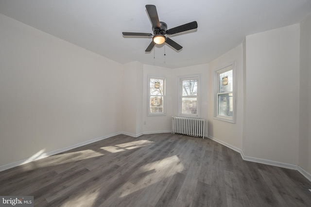 empty room featuring dark hardwood / wood-style floors, radiator, and ceiling fan