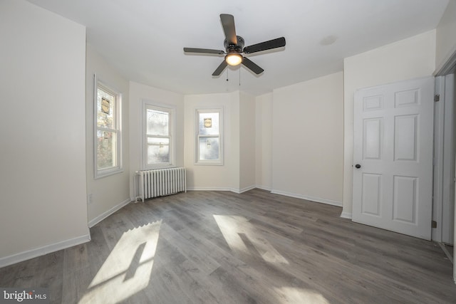 spare room featuring ceiling fan, dark hardwood / wood-style flooring, and radiator heating unit