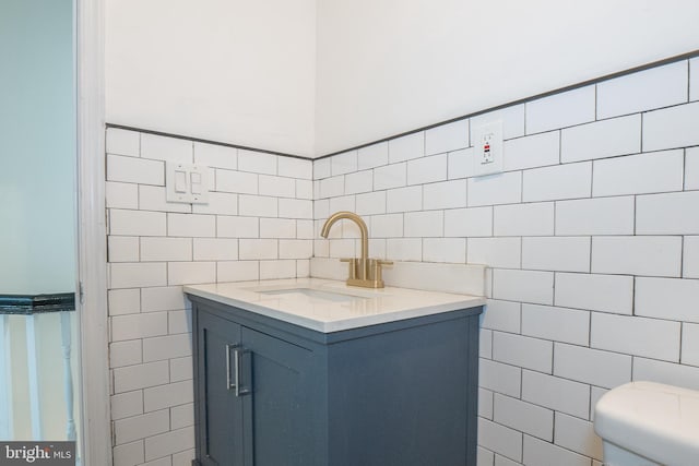 bathroom with vanity, toilet, and tile walls