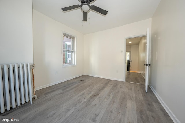 unfurnished room featuring hardwood / wood-style flooring, ceiling fan, and radiator heating unit