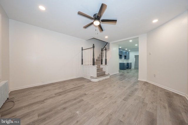 unfurnished living room with radiator, ceiling fan, and light wood-type flooring