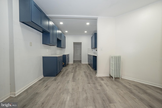 unfurnished living room featuring radiator heating unit and light wood-type flooring