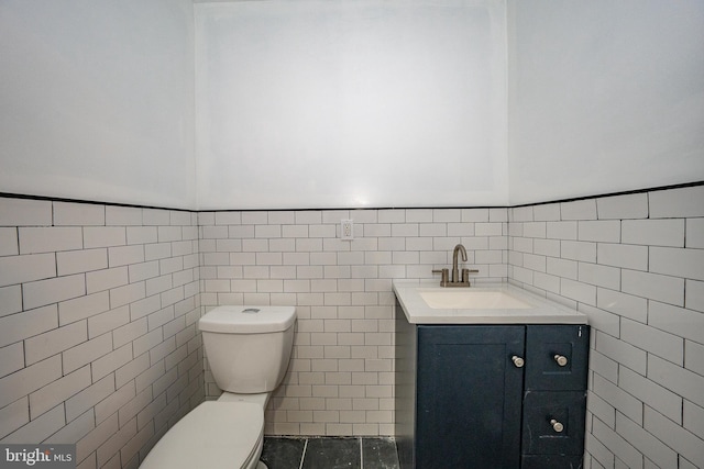 bathroom featuring tile patterned floors, vanity, toilet, and tile walls