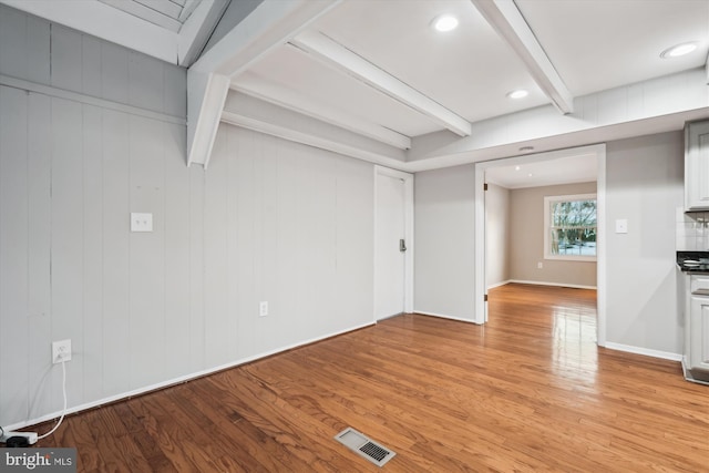 unfurnished living room with light wood-type flooring and beamed ceiling