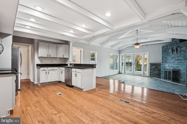 kitchen with ceiling fan, vaulted ceiling with beams, appliances with stainless steel finishes, and light hardwood / wood-style floors