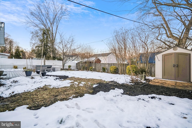 yard layered in snow featuring a wooden deck, a hot tub, and a shed