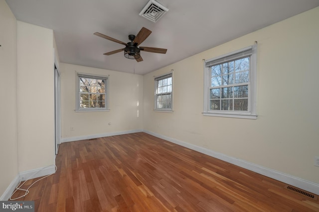 unfurnished room featuring a wealth of natural light, hardwood / wood-style floors, and ceiling fan