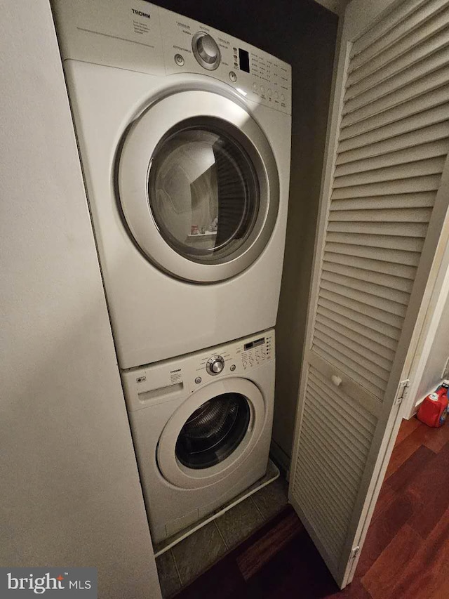 washroom with dark hardwood / wood-style floors and stacked washer / drying machine