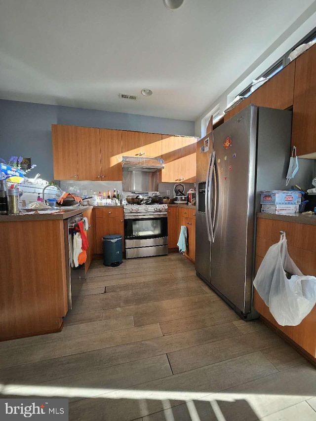 922 Wallace St, Philadelphia, PA 19123 - kitchen featuring appliances with stainless steel finishes, under cabinet range hood, brown cabinets, and dark wood-style flooring
