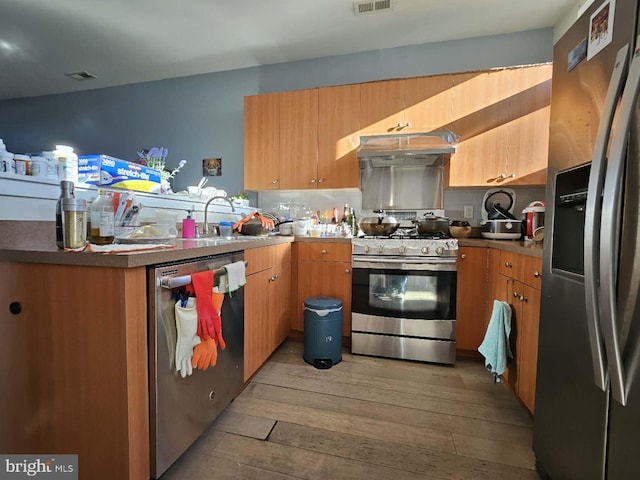 922 Wallace St, Philadelphia, PA 19123 - kitchen featuring stainless steel appliances, light wood-style flooring, a peninsula, under cabinet range hood, and decorative backsplash