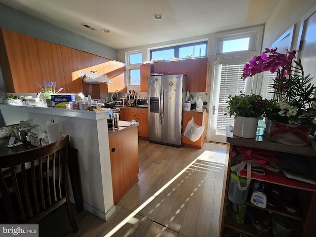 kitchen featuring kitchen peninsula, stainless steel fridge, and light hardwood / wood-style flooring