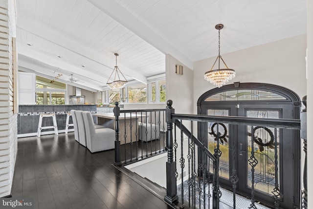 foyer entrance with dark hardwood / wood-style floors, a chandelier, and lofted ceiling with beams