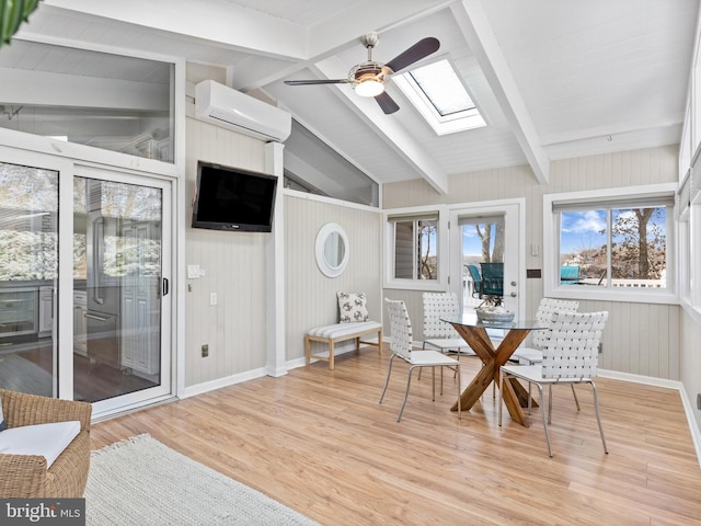 sunroom / solarium featuring ceiling fan, vaulted ceiling with skylight, and a wall mounted AC