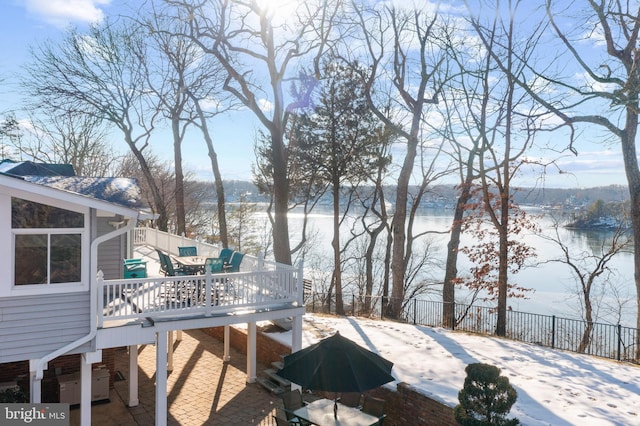 yard covered in snow with a deck with water view and a sunroom