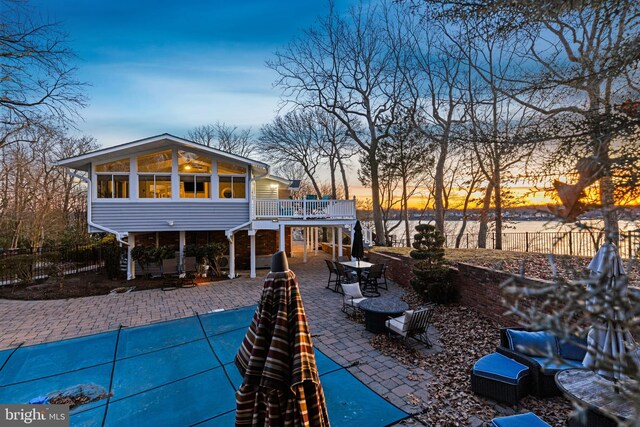 exterior space featuring a sunroom, a patio, and a water view