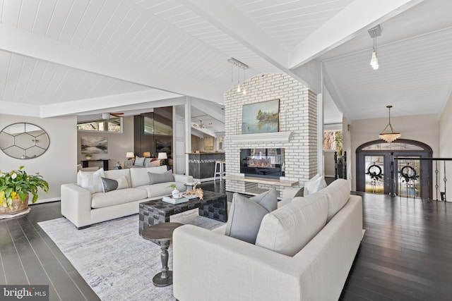 living room featuring lofted ceiling with beams, dark wood-type flooring, and a fireplace