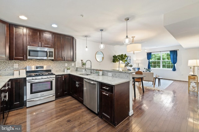 kitchen with sink, hanging light fixtures, stainless steel appliances, dark hardwood / wood-style flooring, and kitchen peninsula