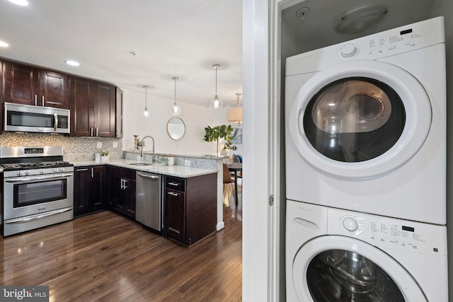 clothes washing area with dark hardwood / wood-style floors, stacked washing maching and dryer, and sink