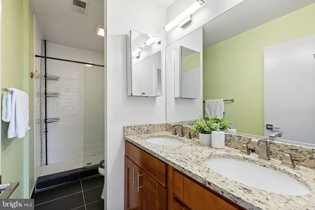 bathroom with tile patterned floors, vanity, tiled shower, and toilet