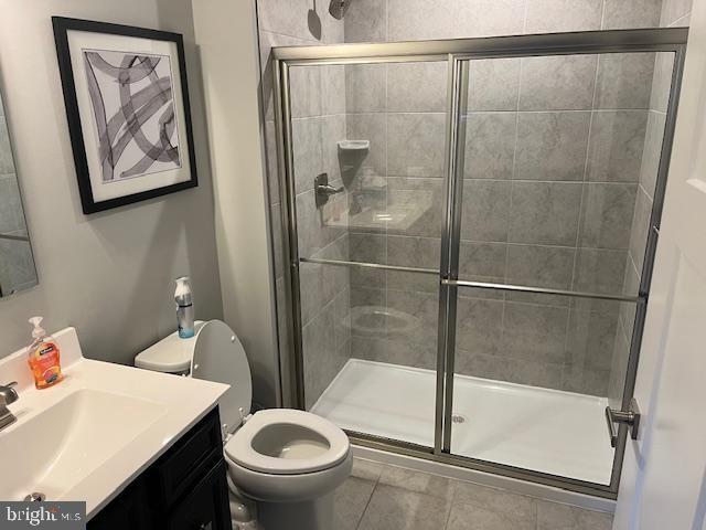 bathroom featuring tile patterned floors, vanity, toilet, and a shower with shower door