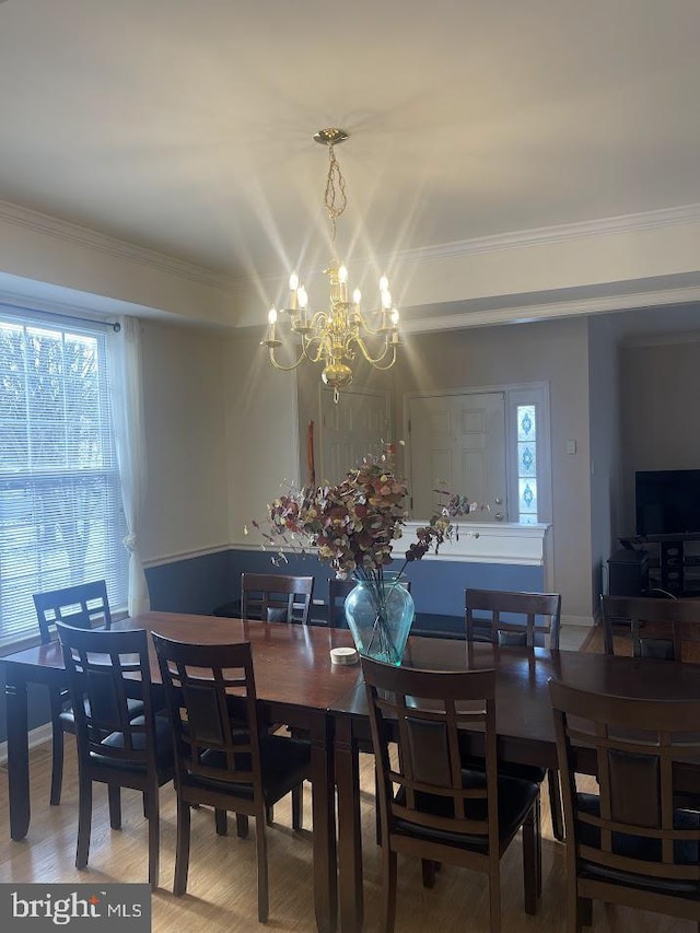 dining space featuring hardwood / wood-style floors, ornamental molding, and an inviting chandelier