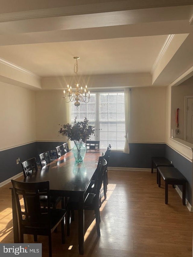 dining area with hardwood / wood-style floors, a tray ceiling, crown molding, and a notable chandelier