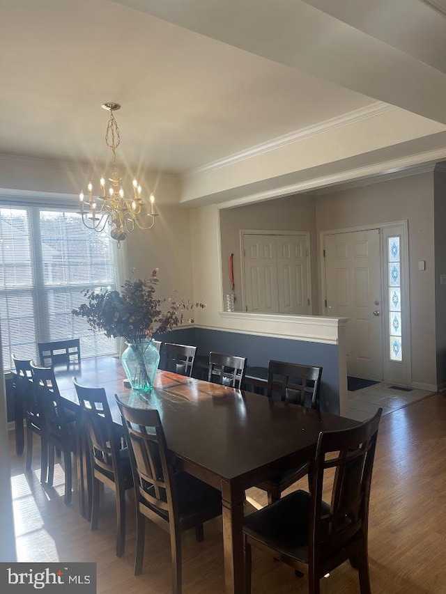 dining room featuring crown molding, wood-type flooring, and a notable chandelier