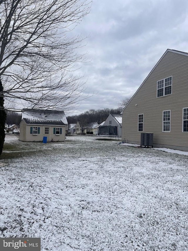 yard covered in snow with central AC unit and an outdoor structure