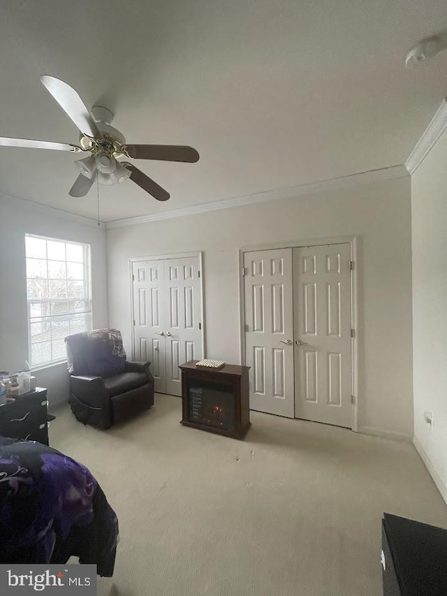 carpeted bedroom with ceiling fan, two closets, and ornamental molding