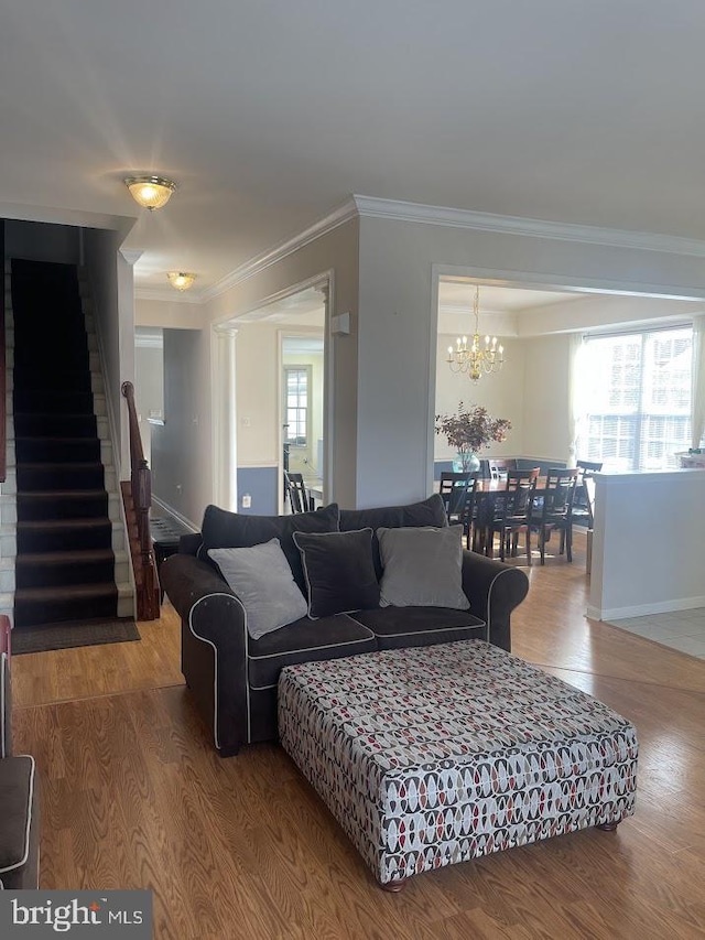 living room featuring hardwood / wood-style floors, an inviting chandelier, plenty of natural light, and crown molding