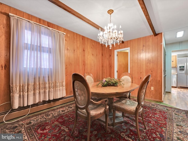 dining space featuring beam ceiling, an inviting chandelier, a baseboard heating unit, and wooden walls